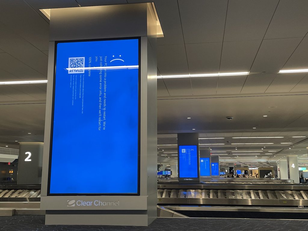 All advertisement and information screens at baggage conveyor belt at airport giving microsoft blue screen of death error