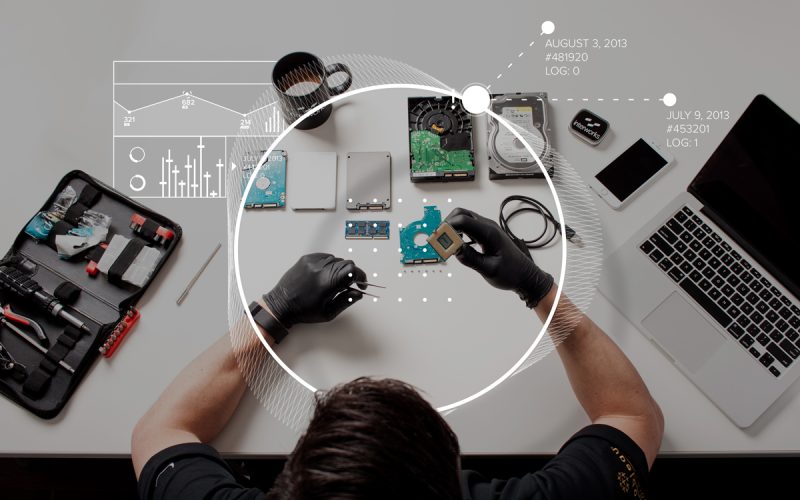 Digital Forensics Investigator with tool box, hard drive, SSD and laptop on a table and processor in hand examining evidences wearing gloves