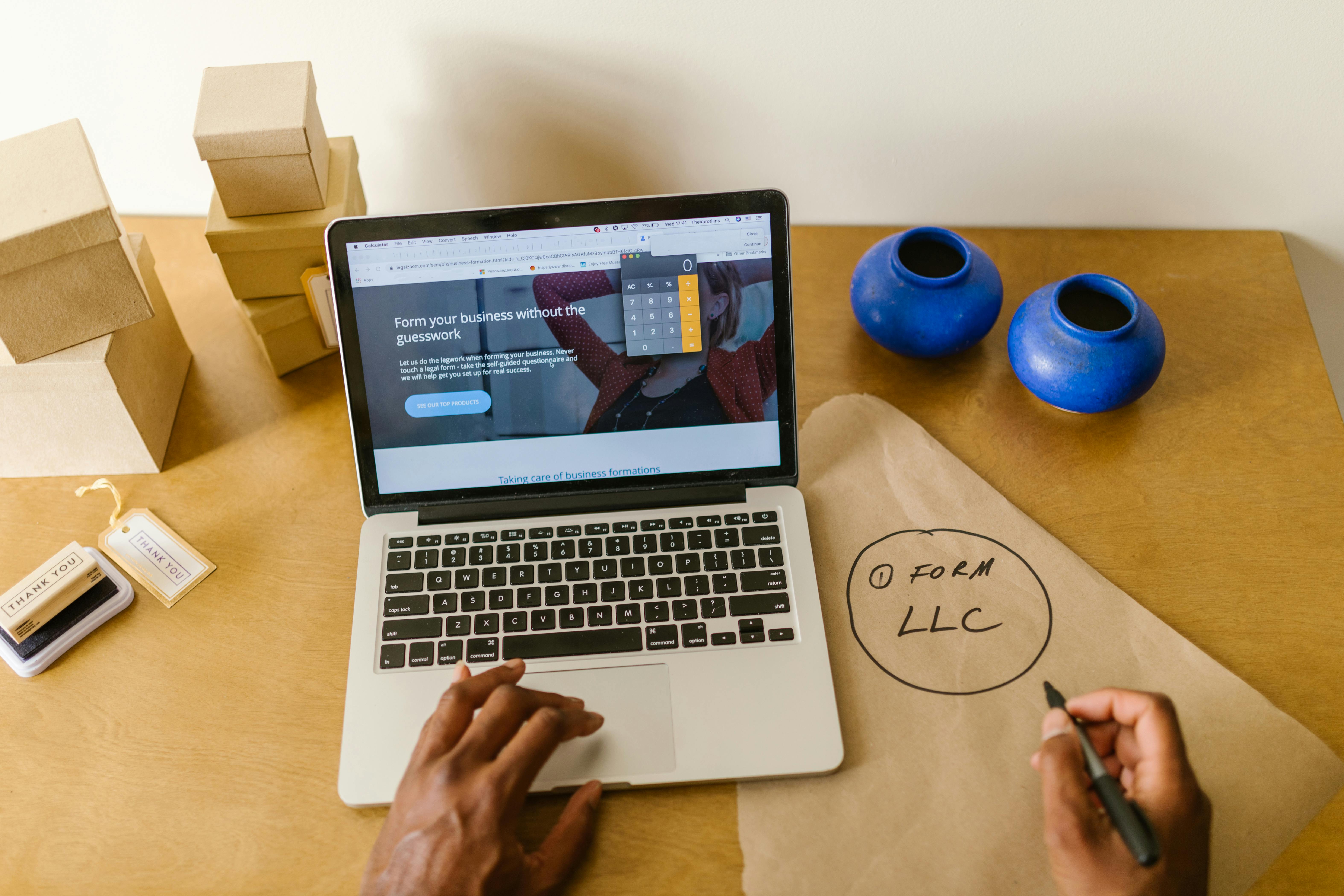 Laptop on a table and Form LLC written on a paper beside it on a table