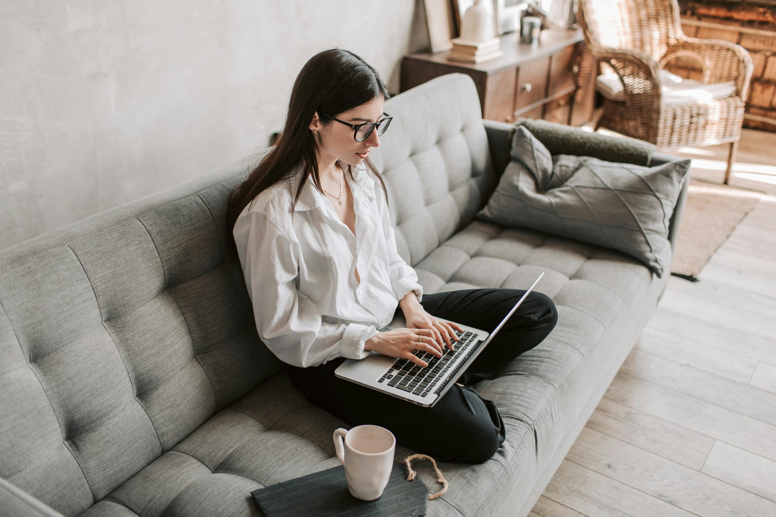 Girl sitting on a sofa in her home working at her laptop for online business