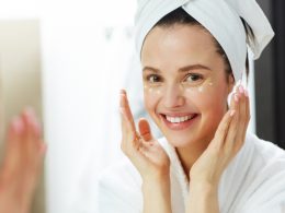 Smiling girl applying cream on her face