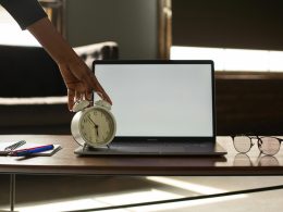 A laptop and an alarm clock on a table