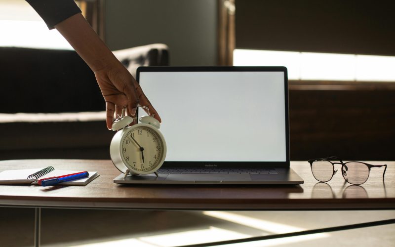 A laptop and an alarm clock on a table